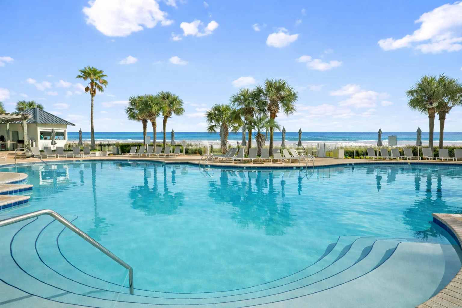 Resort pool with palm trees and the Gulf beyond, High Tide Penthouse