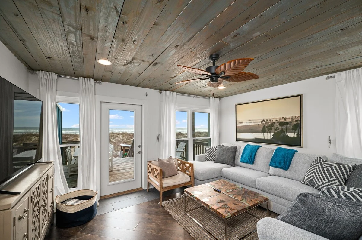 Living room with TV and doors to the Gulf-view balcony, SouthWind West