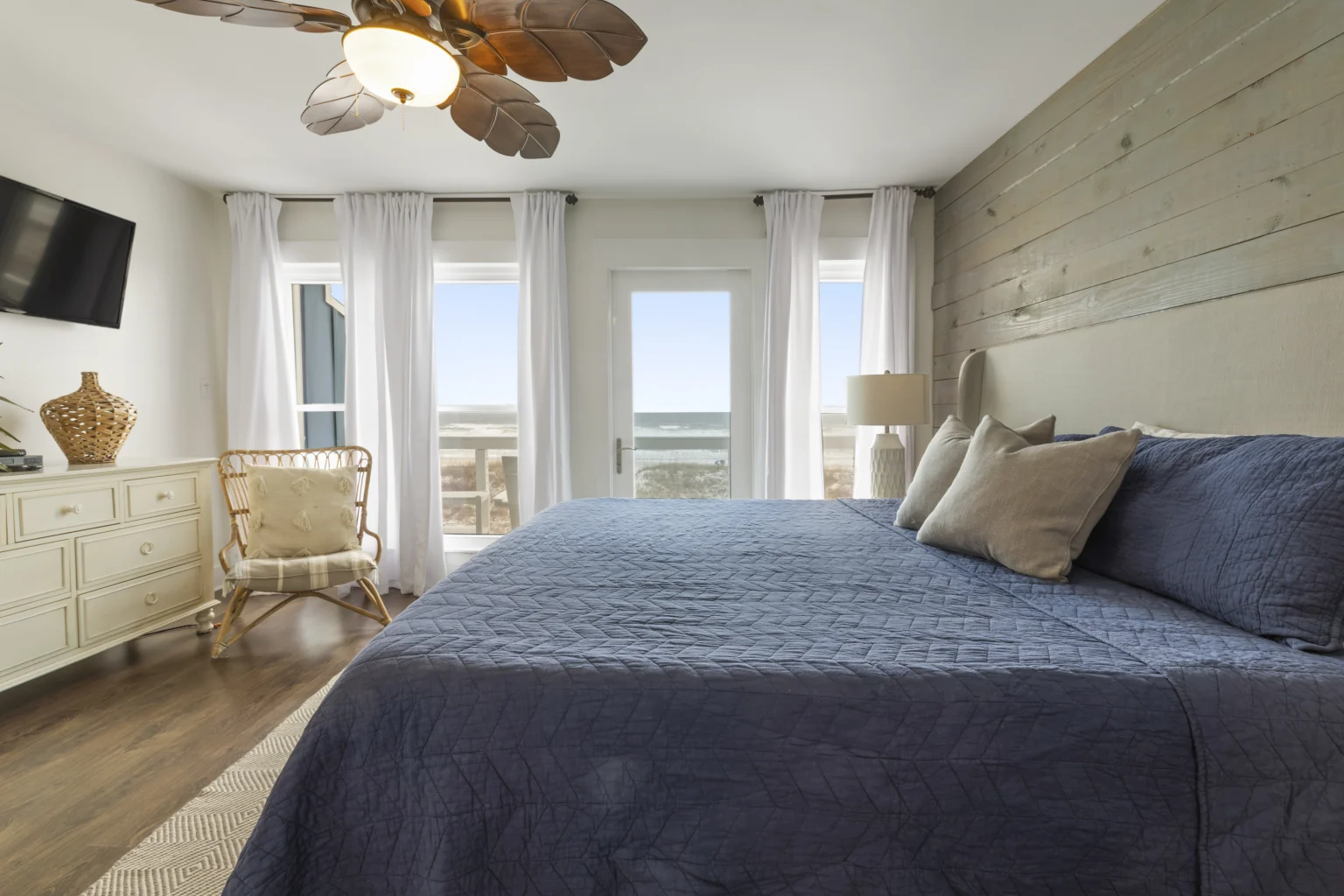 King bedroom with navy bedding and Gulf-view windows, SouthWind West