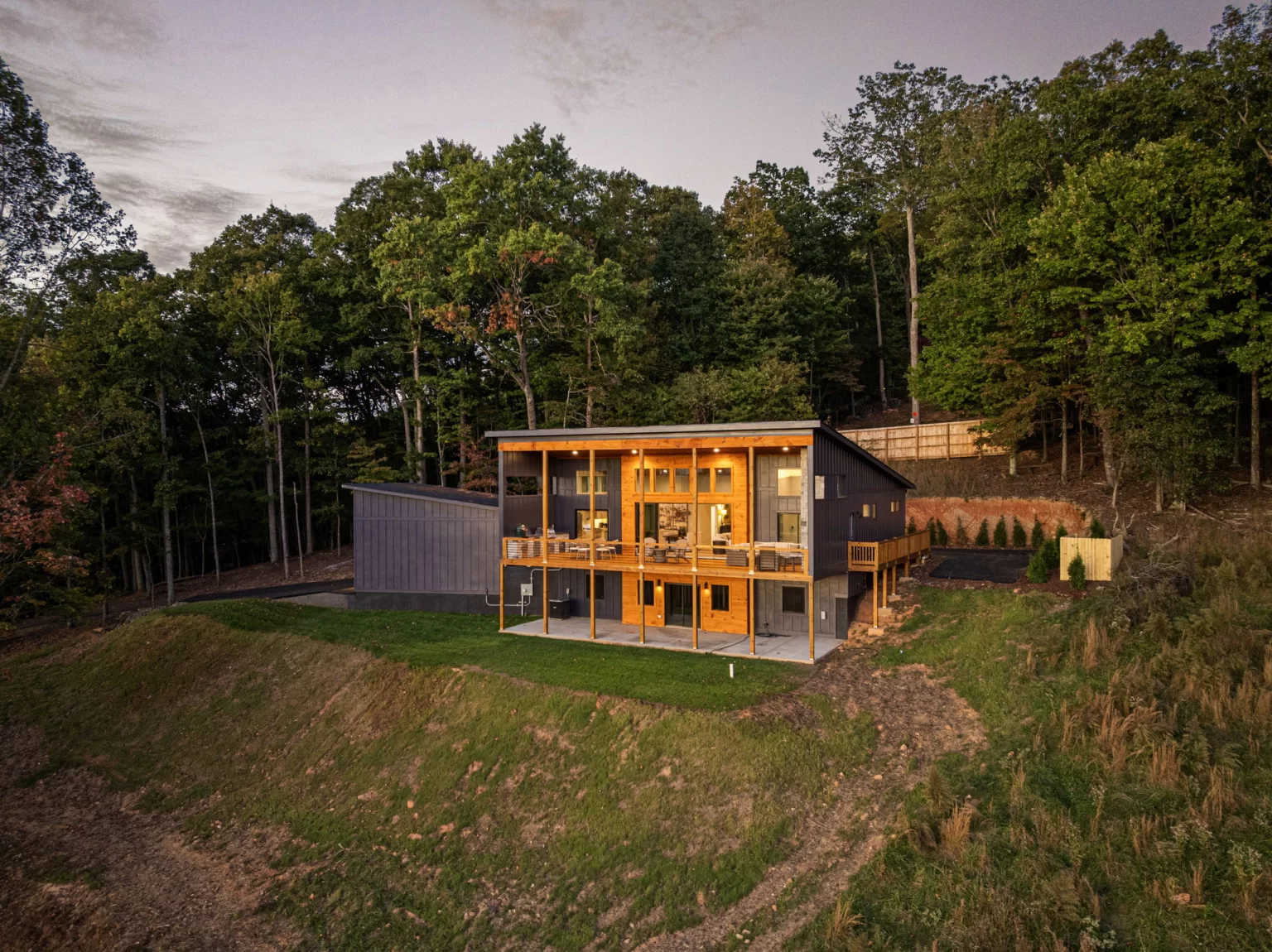 Home at dusk on its wooded lot, from above, View Finder II